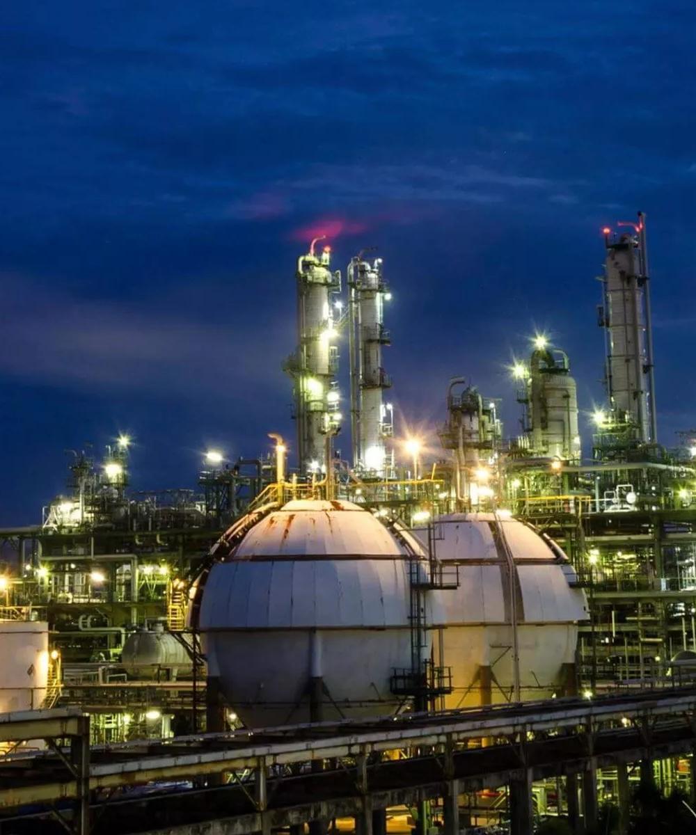View of a lit up petrochemical refinery plant at night.