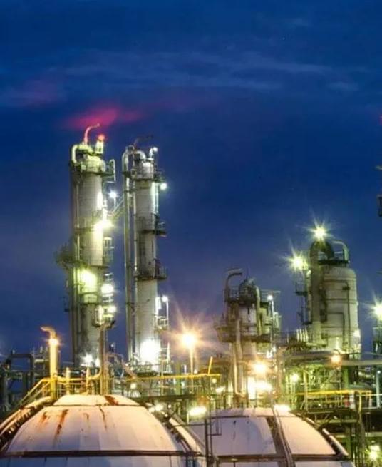 View of a lit up petrochemical refinery plant at night.