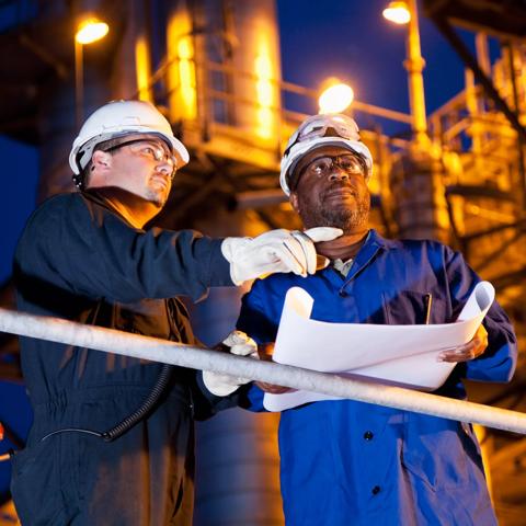 Multi-ethnic engineers working at chemical plant at night.