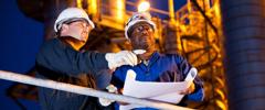 Multi-ethnic engineers working at chemical plant at night.