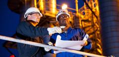 Multi-ethnic engineers working at chemical plant at night.