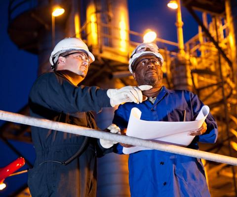 Multi-ethnic engineers working at chemical plant at night.