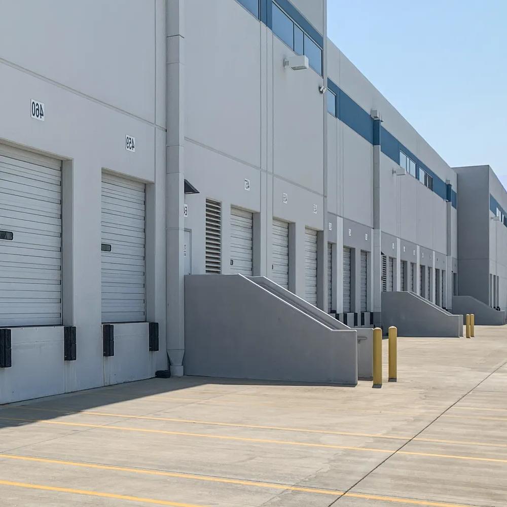 The exterior of a storage warehouse with several white loading bay doors.