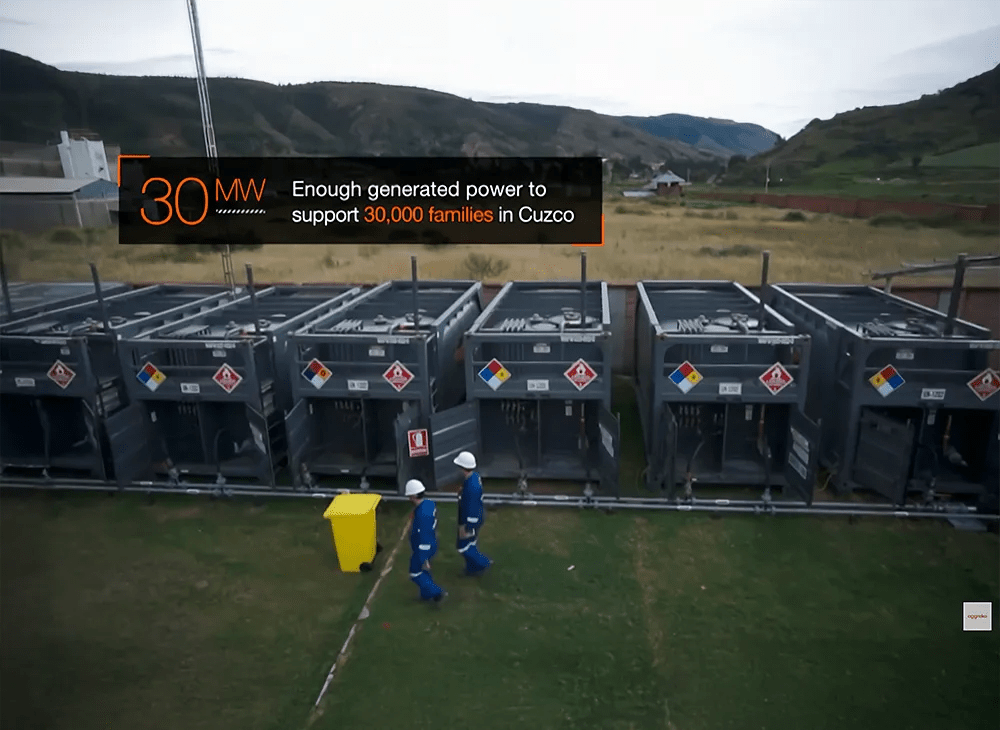 Aerial view of 2 workers in uniform walking past a row of generators.