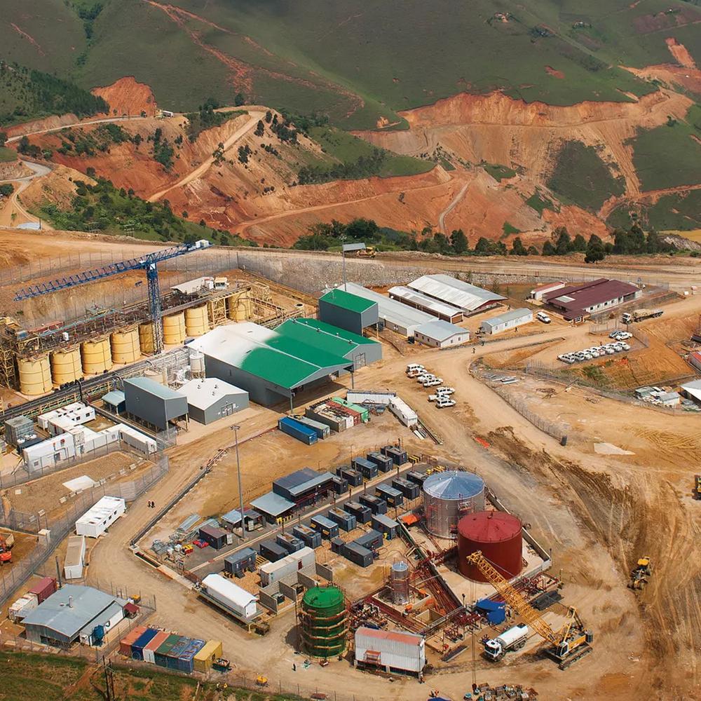 An aerial shot of a mining complex in a valley, showing industrial buildings. 