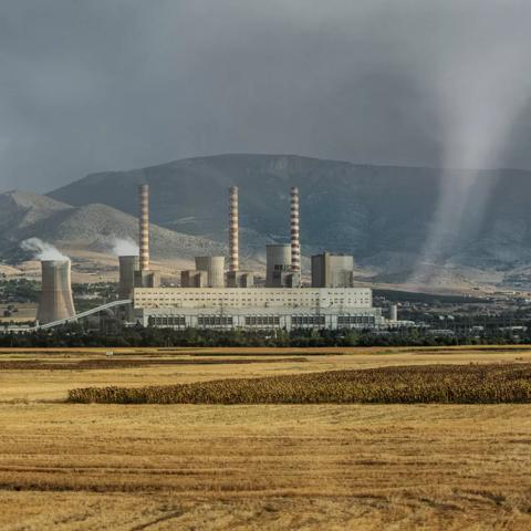 A power plant with cooling towers in a cloudy, mountainous area.