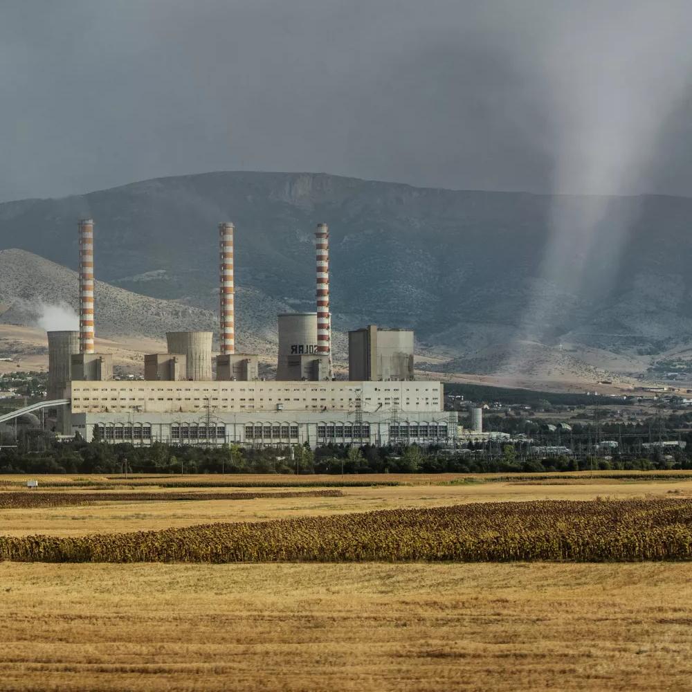 A power plant with cooling towers in a cloudy, mountainous area.