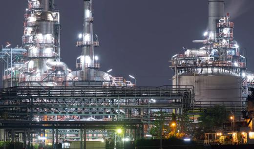 Oil refinery industrial district at night with tank farm and pipe line.