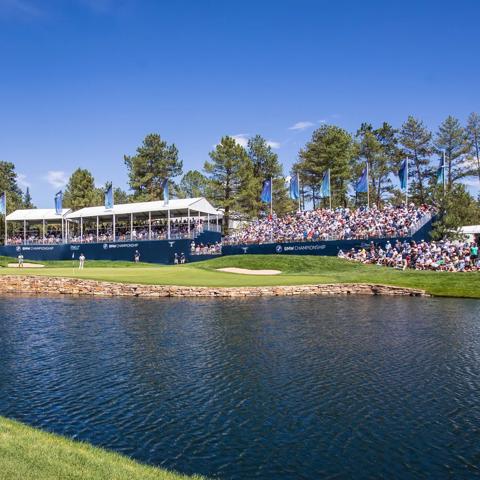 Golf players on a green field and a crowd watching from the stands at the BMW Championship Tournament