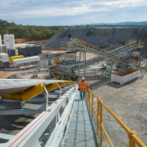 View of a worker in uniform walking down some stairs in a construction site.