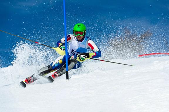 Front view of adult alpine skier at the blue pole during the slalom ski race