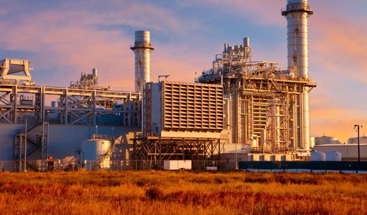 Natural gas fired turbine power plant with it's cooling towers rising into sunset sky