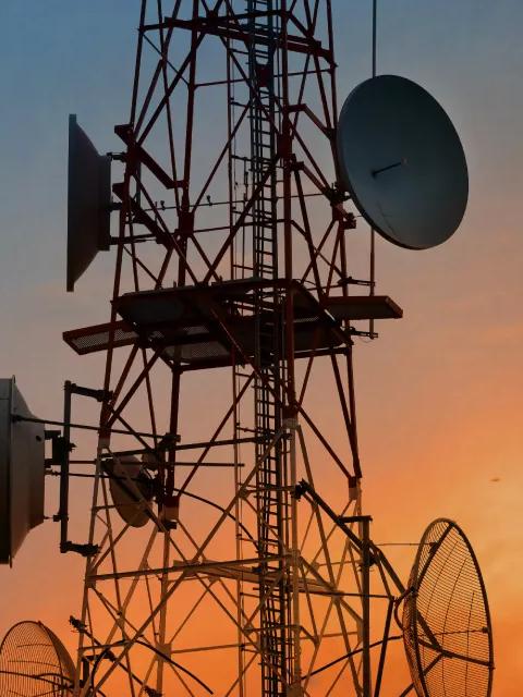 Gros plan sur une tour de télécommunications au coucher du soleil.