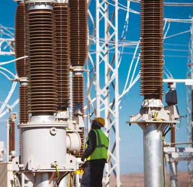 Electric plant with multiple transmission towers connected to each other against a blue sky in a yellow field