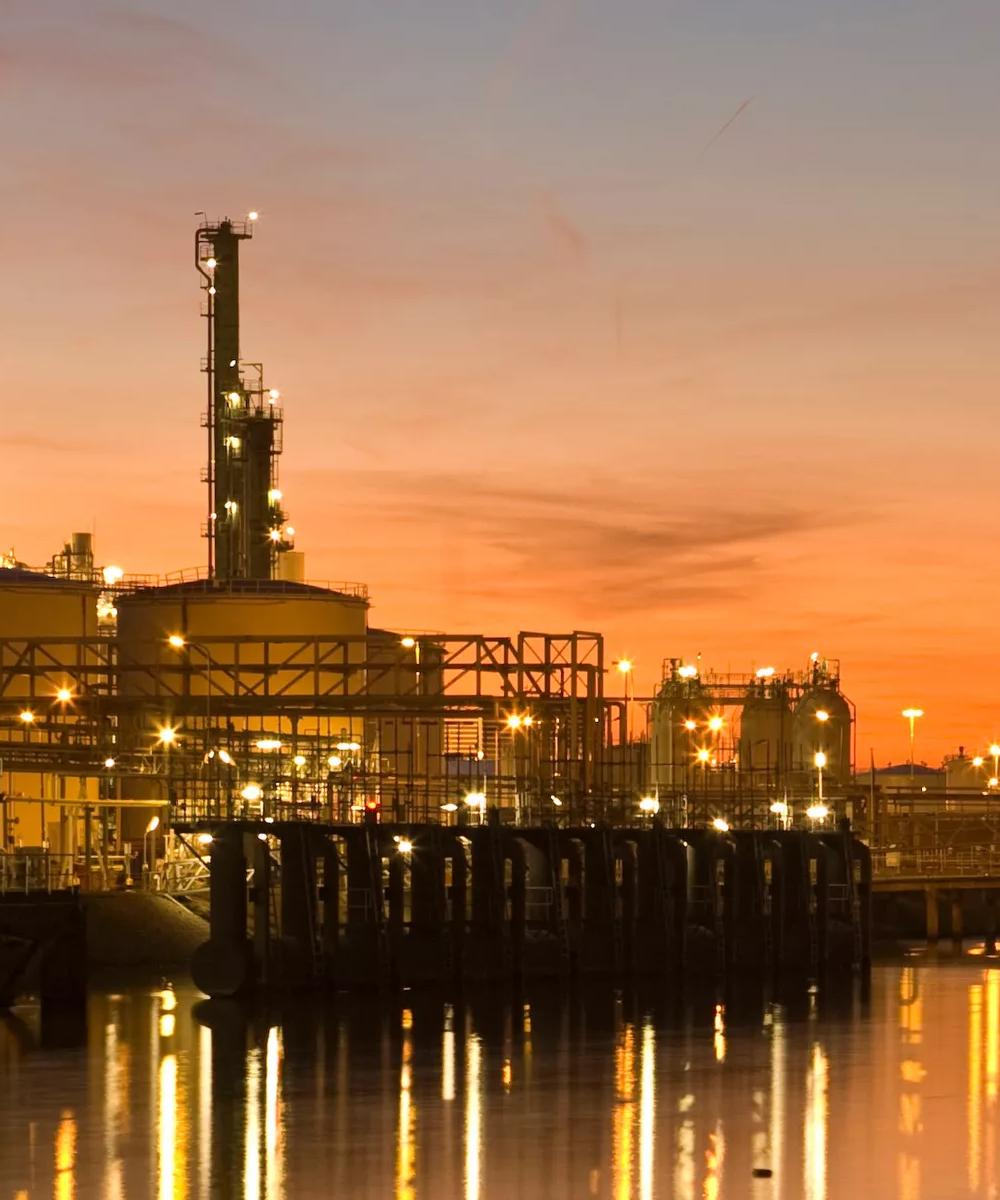Panoramic view of a refinery with an orange sunset background.