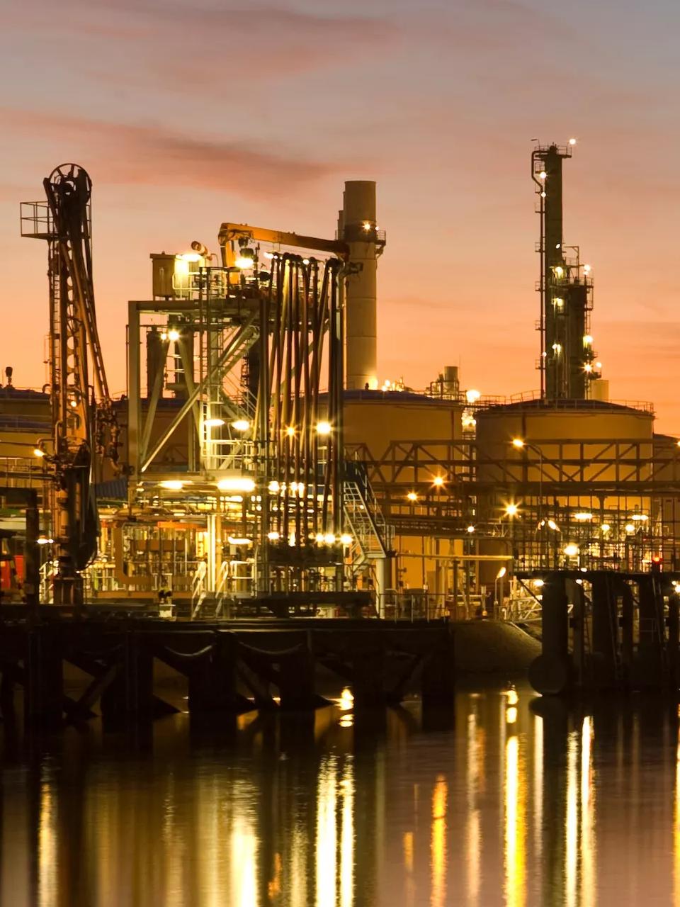 Panoramic view of a refinery with an orange sunset background.