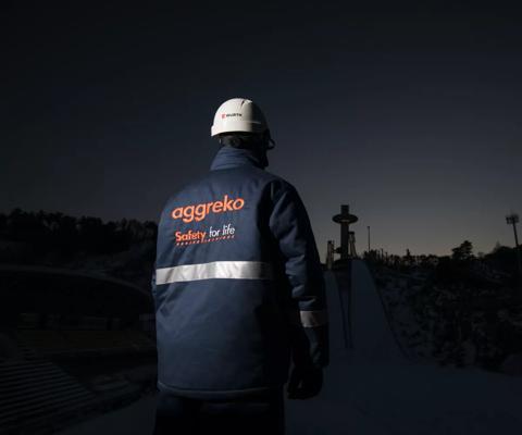A worker in a dark setting wears a jacket with 