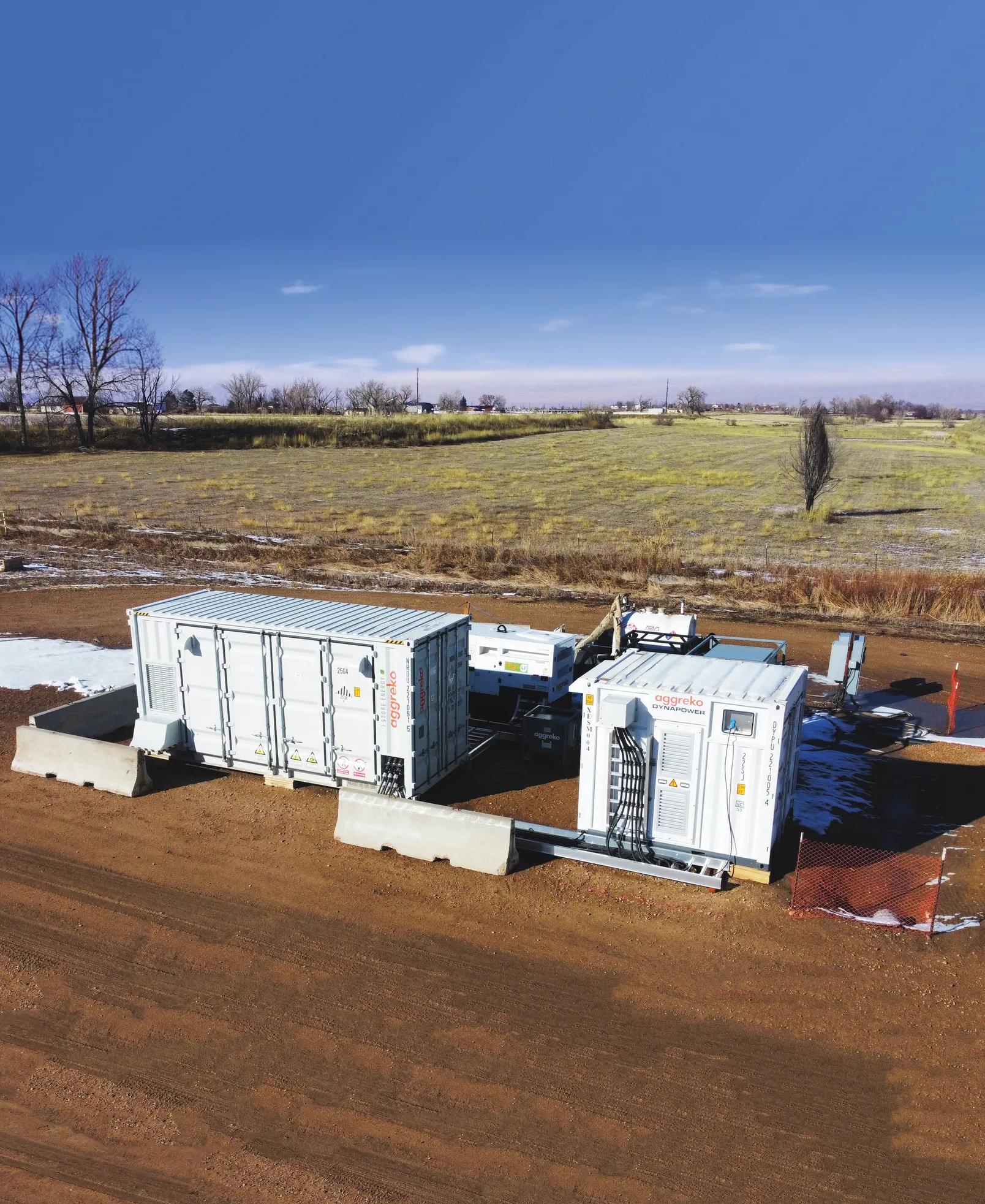 Two white Aggreko batteries at a worksite