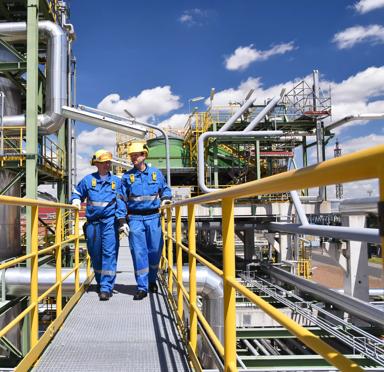 chemical industry plant - workers in work clothes in a refinery with pipes and machinery