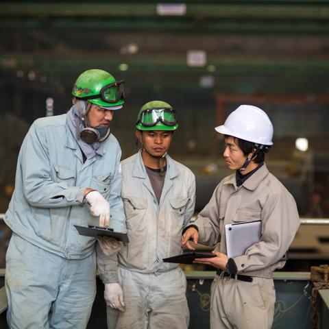Three workers meeting and talking in an industrial setting