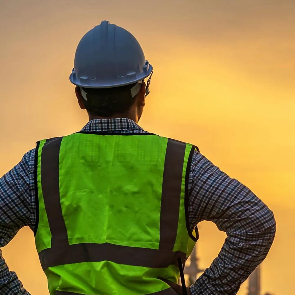 Worker in uniform looking at the sunset in the distance.