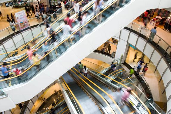  Three different floors inside a shopping mall with blurry people going up and down the electric staircases
