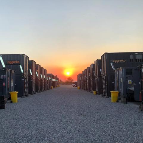 Multiple rows of double-stacked industrial units with the Sun setting in the background.