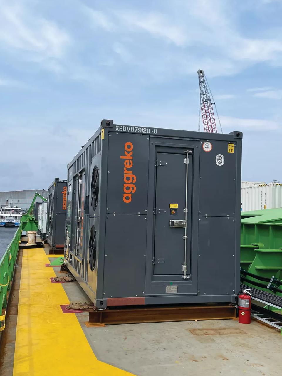 A large grey generator on a barge on a river