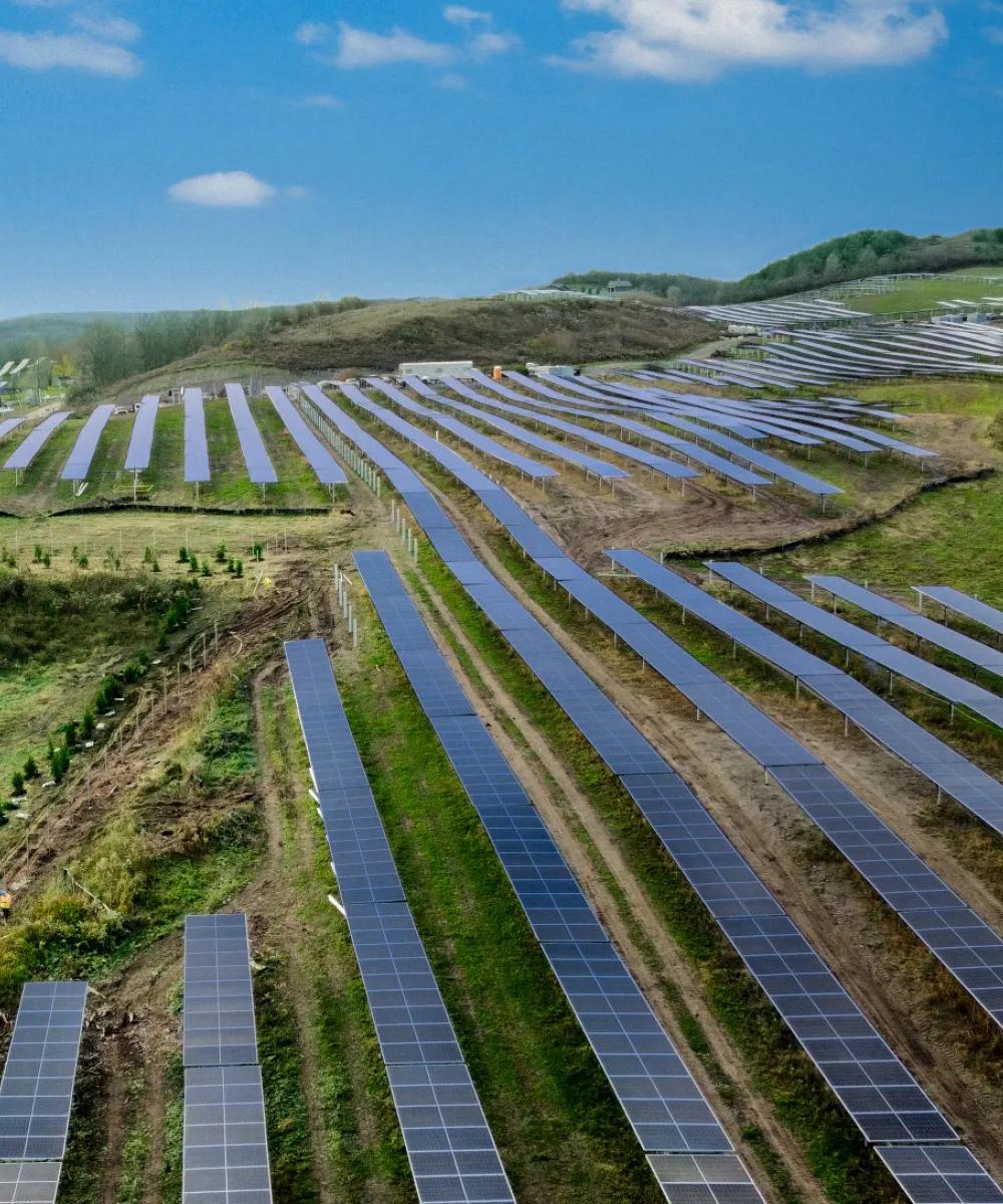 Aerial view of vertical multiple rows of solar panels in a grass field.