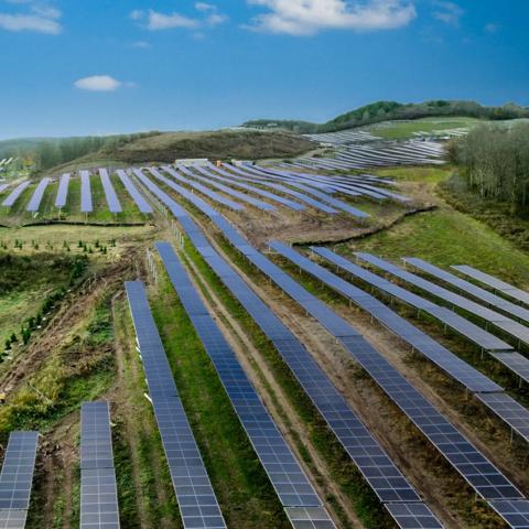 Aerial view of vertical multiple rows of solar panels in a grass field.