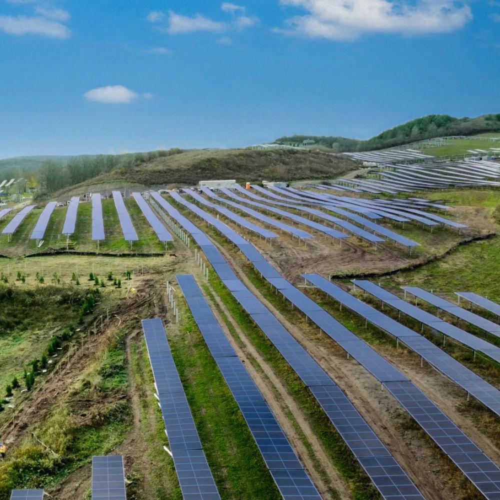 Aerial view of vertical multiple rows of solar panels in a grass field.