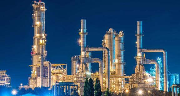 Distance view of a lit-up refinery at night.