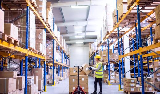 Young female warehouse worker loading up a pallet truck with boxes.