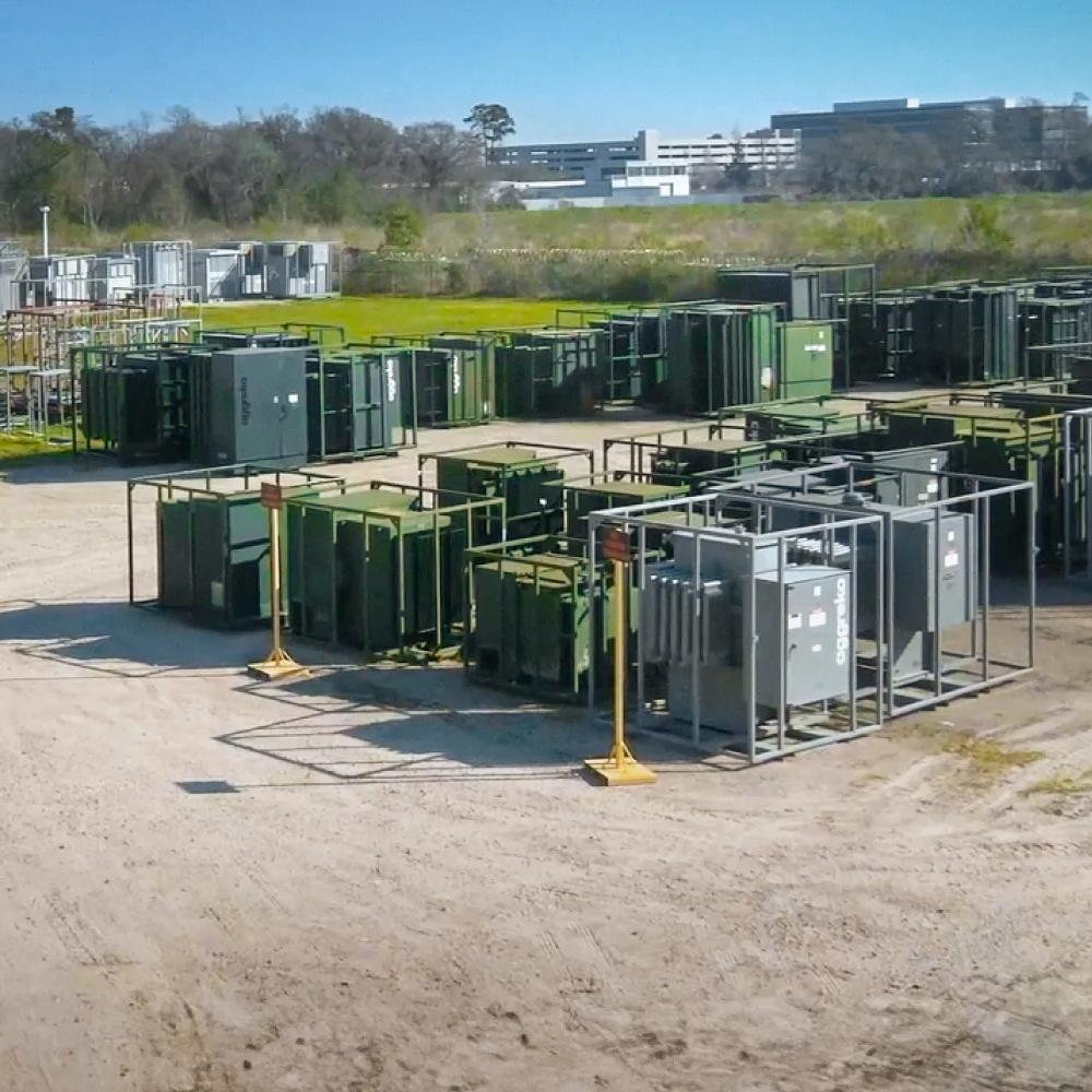 View of multiple Aggreko grey transformers amongst other green equipment at a worksite 