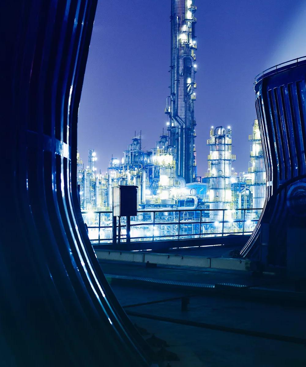View of a modern, lit-up refinery at night at a distance.