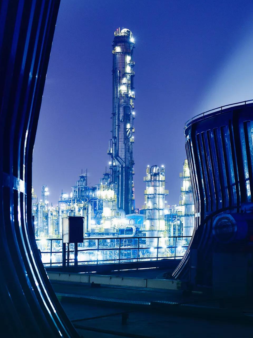 View of a modern, lit-up refinery at night at a distance.