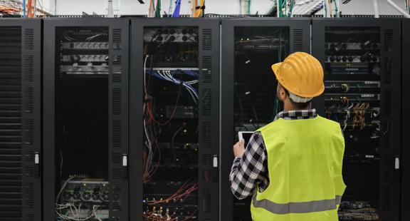 Young technician man working with tablet inside big data center room full of rack servers - Focus on man head