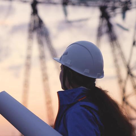 An electrician at a high voltage power plant works with a project at sunset in the sky, electrical energy design, industry concept, modern business technology, an engineer in the glare of the sun.