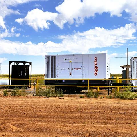 An outdoor panoramic view of a containerized hybrid energy solution installed on in a desert-like landscape