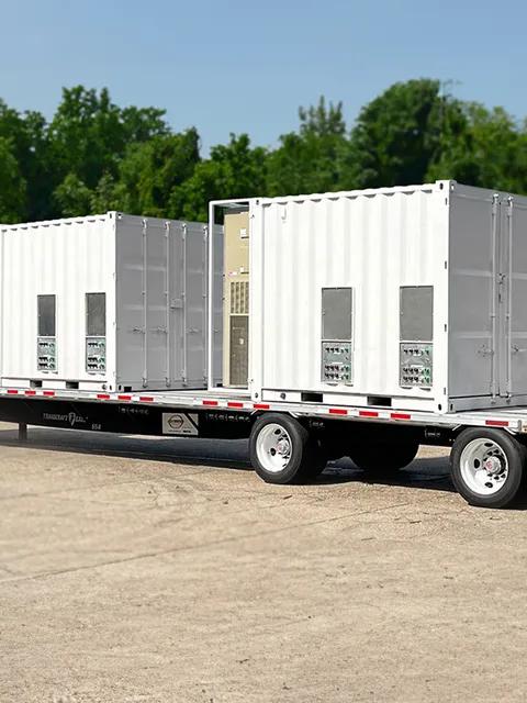 White industrial equipment containers mounted on a flatbed trailer.