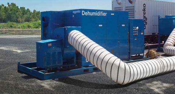 Two blue Dehumidifiers connected by a large, white flexible duct sitting on pavement. 