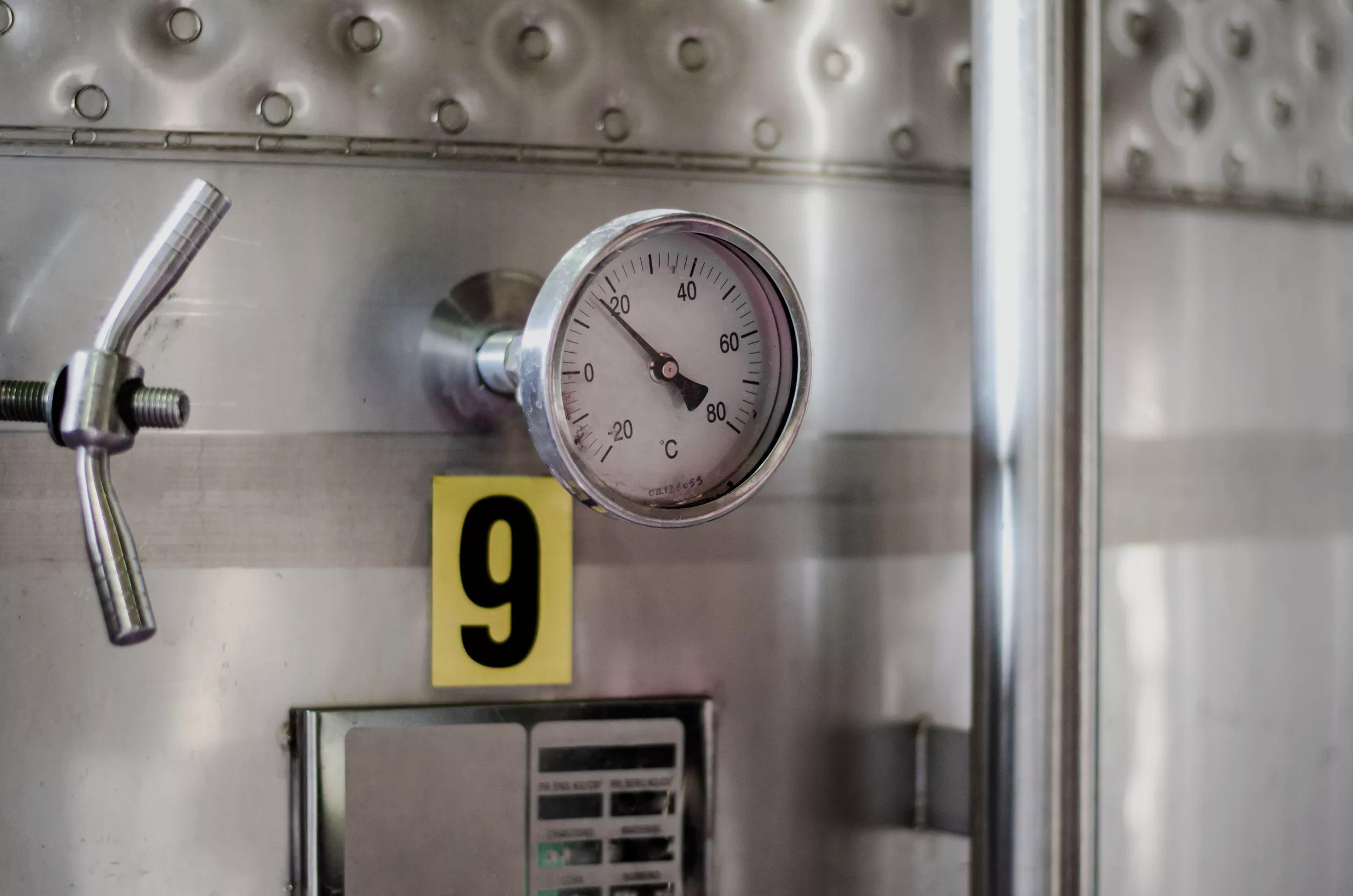 Close up of a gauge attached to grey equipment 