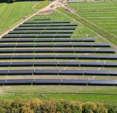 Aerial view of horizontal multiple rows of solar panels in a grass field.