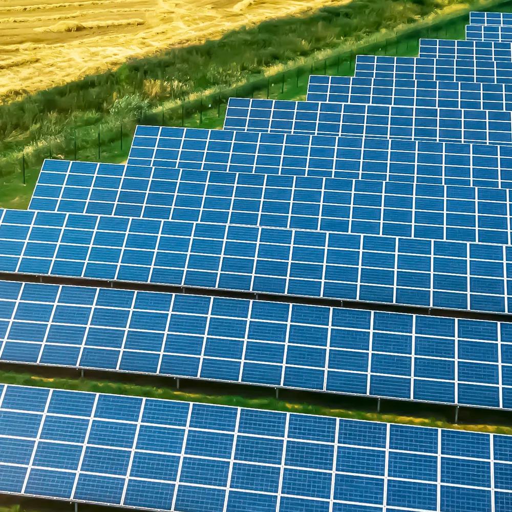 Aerial view of a large row of solar panels in a grassy field.