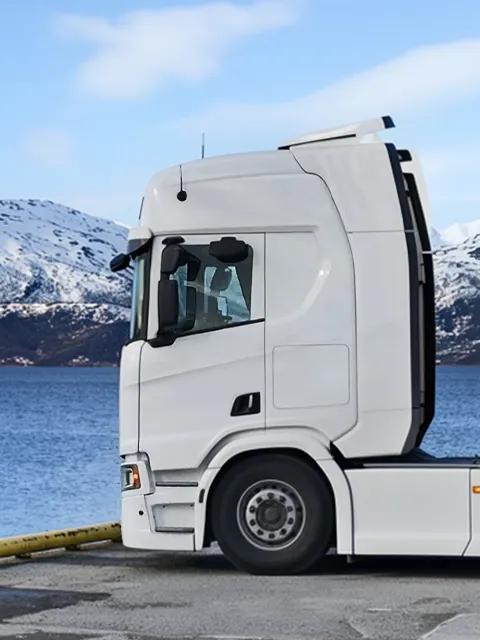 Équipement Aggreko transporté par camion, au pied d’un paysage montagneux enneigé.