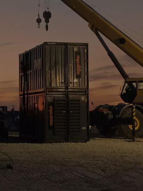 Industrial equipment and a crane at a construction site during sunset.