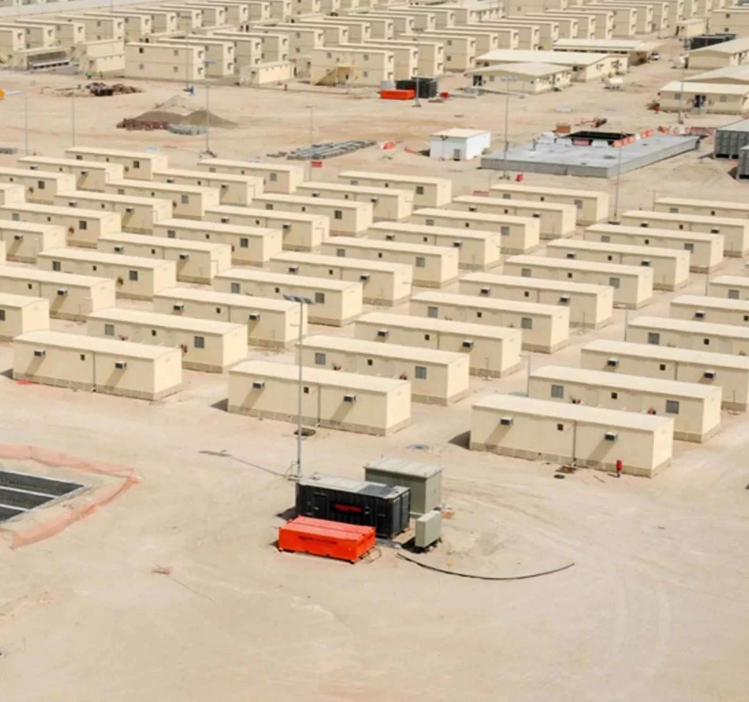 An aerial view of a large camp with many temporary, modular buildings arranged in rows