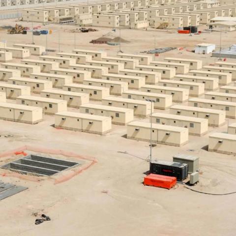 An aerial view of a large camp with many temporary, modular buildings arranged in rows