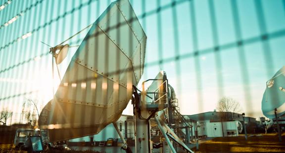 View of an antenna through a fence.