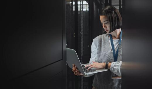 Woman with laptop, datacenter and information technology, engineer and server room with software update. Tech industry, cybersecurity and network with Asian female setting up firewall and database.